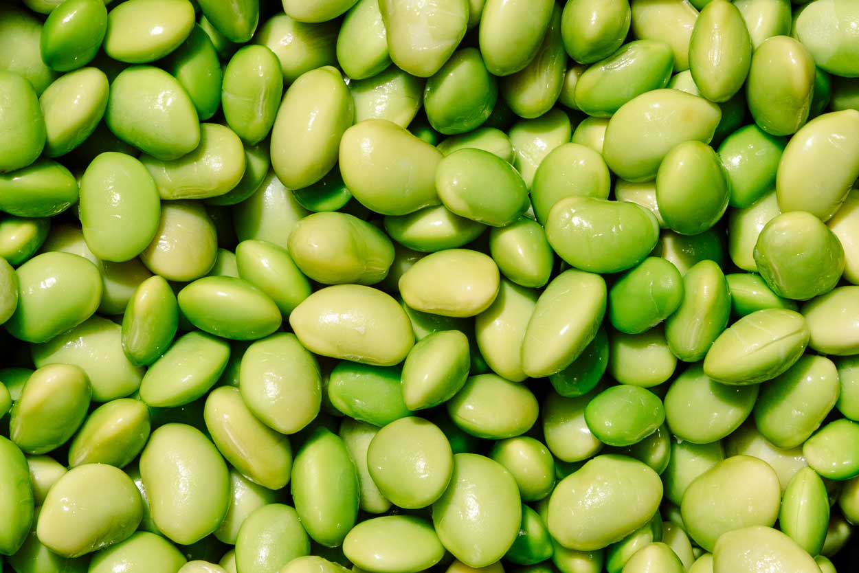 Tongs placing marinated meat into the hotpot.