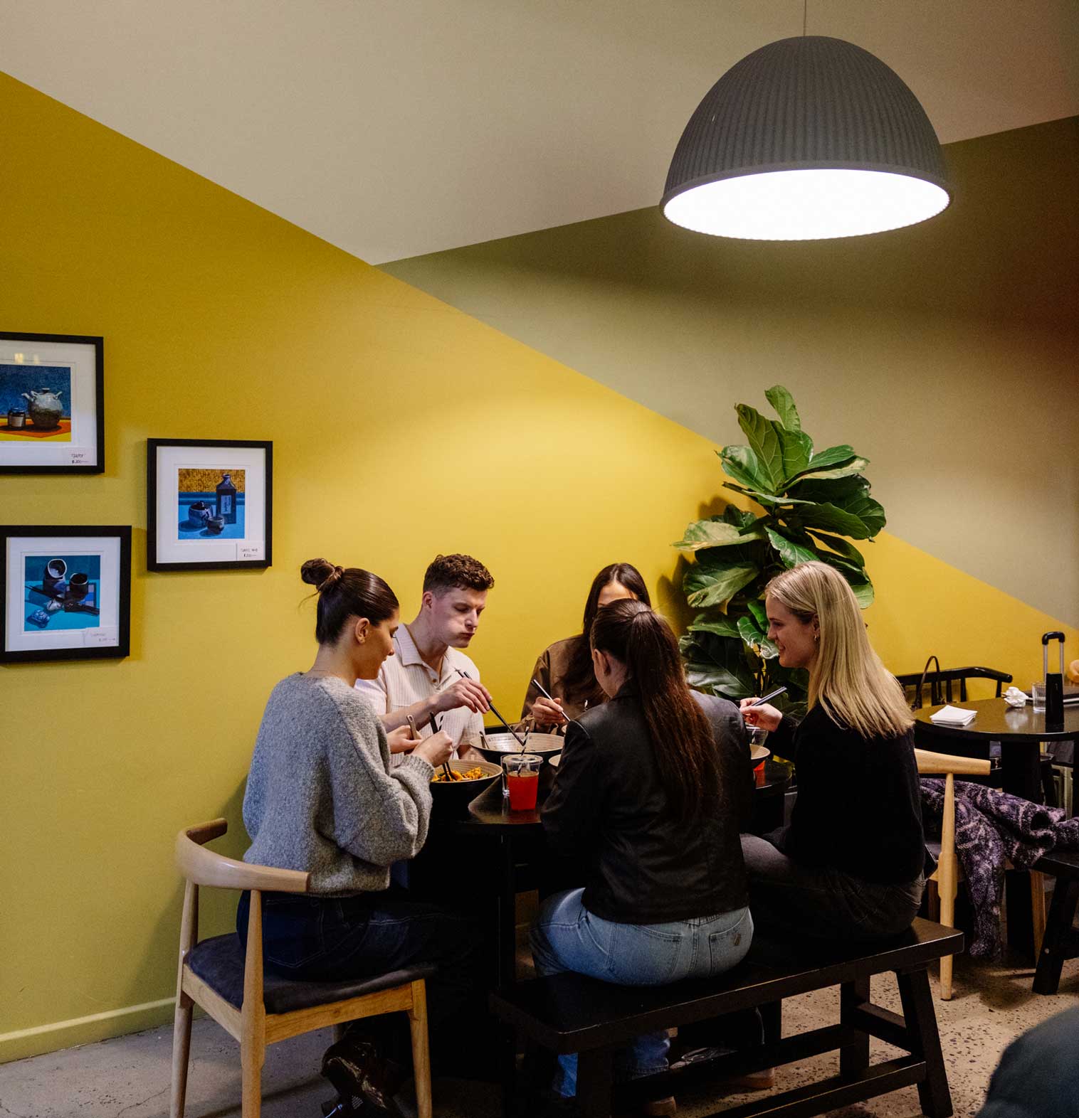 Friends clinking chopsticks over a shared meal.